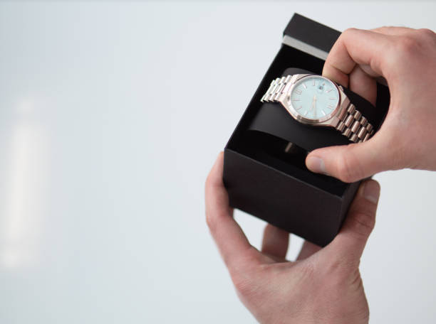 istock close up of man hands picking up taking a wrist watch from a box 2020970534