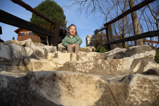 Smiling 7 year old male child looks through balusters of railing on wooden staircase.
