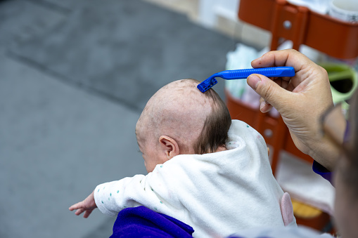 baby girl shaving her hair with sharp razor. shaving hair for 1 month