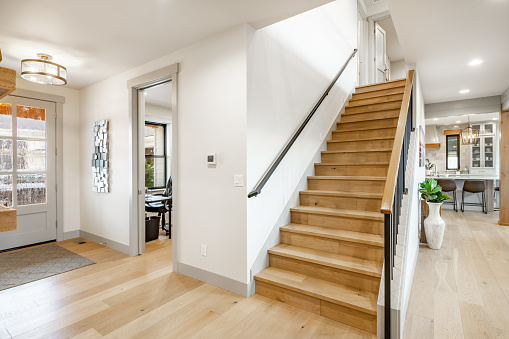 Beautiful home painted white with a modern farmhouse vibe. Entrance foyer to a lovely home with hardwood floors large staircase with wrought iron metal railings, post and beam entry. Decorated with simple furniture and a very welcome feeling.
