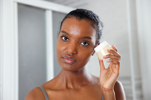 Fierce Beautiful Black Woman Holding A Cream Near Face in the Morning, Italy