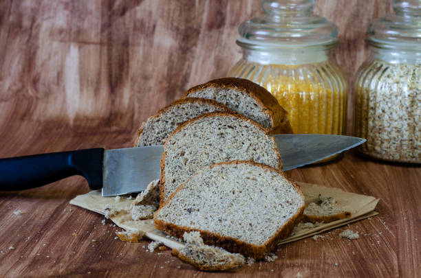 Delicious whole grain bread piece on the piece. A type of black bread that is particularly healthy and good to eat in a diet placed on a napkin with a background in the color of natural wood and with two bowls of cereal and kitchen knife