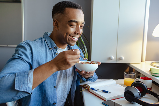 Young African American man home eating healthy breakfast at home