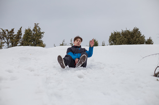 Young man sledding down hill  on  a cold winter day