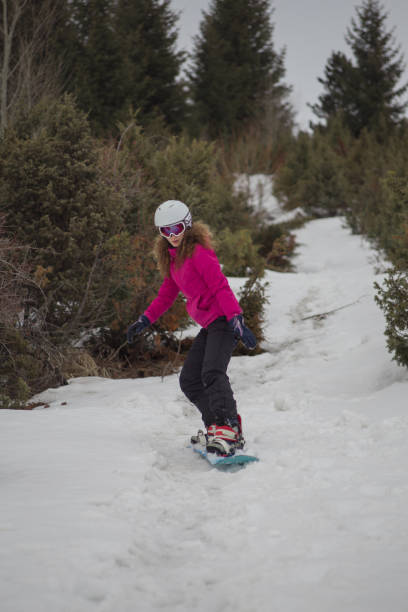 istock Young woman snowboarding down hill on winter vacation 2021151696