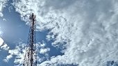 An antenna tower with a cloudy blue sky in the background.