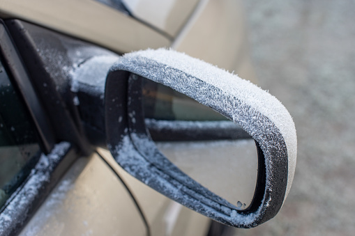 Frost forms on a car mirror. Frozen side mirror of a car in winter.