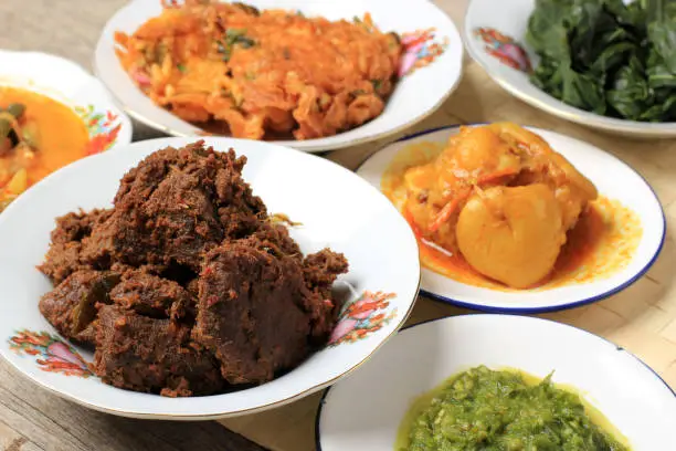 Photo of Rendang Padang. Spicy beef stew from Padang, Indonesia. The dish is arranged among the other menu from warung nasi Padang.