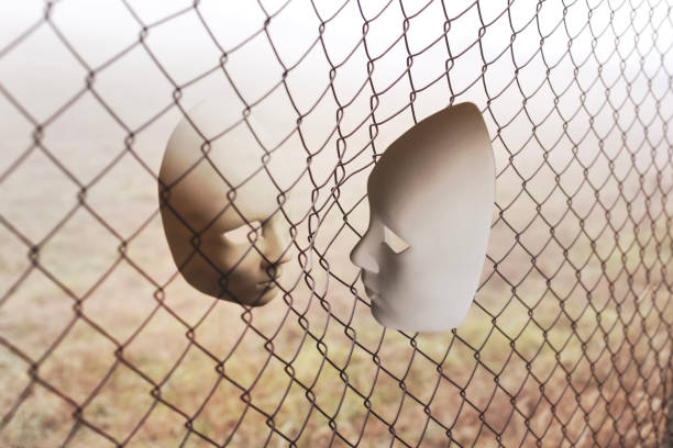 surreal face to face between two masks divided by a metallic net, abstract concept