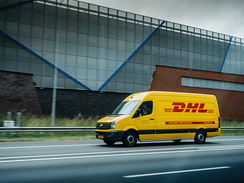 Amsterdam, Netherlands - Aug 23, 2021: Side view of fast driving DHL fast delivery Volkswagen van on the Dutch highway
