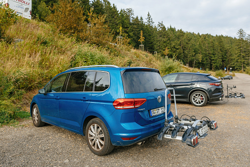 Mummelsee, Germany - Sep 22, 2018: Rear view at the lava blue colored Volkswagen Touran van with bike carriage system parked on empty parked near hiking road in the Black Forest - tilt-shift lens used