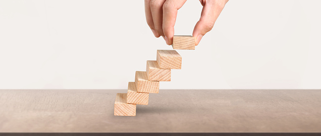 Hand liken business person stepping up a toy staircase