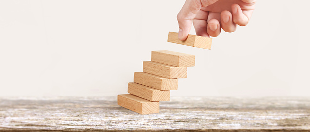 Hand liken business person stepping up a toy staircase