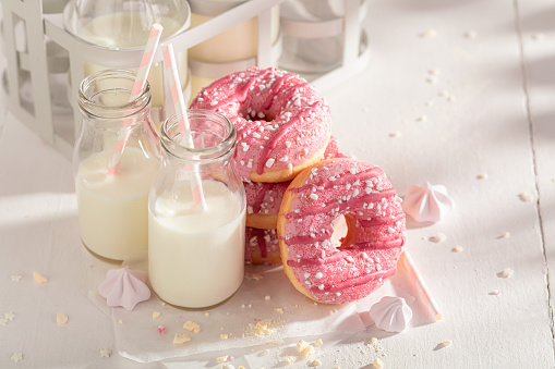 Fresh and tasty pink donuts as popular snack. Served with milk. Most popular dessert.