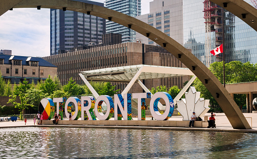 Toronto, Canada - 06 05 2021: Summer view on new TORONTO sign behind fountain in the heart of Toronto city - Nathan Phillips Square beside the City Hall at the intersection of Queen Street West and Bay Street.