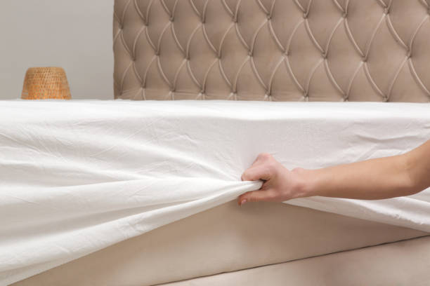 istock Changing bed sheets. Woman is putting on a fitted white cotton sheet on a mattress while making the bed. 2021293056