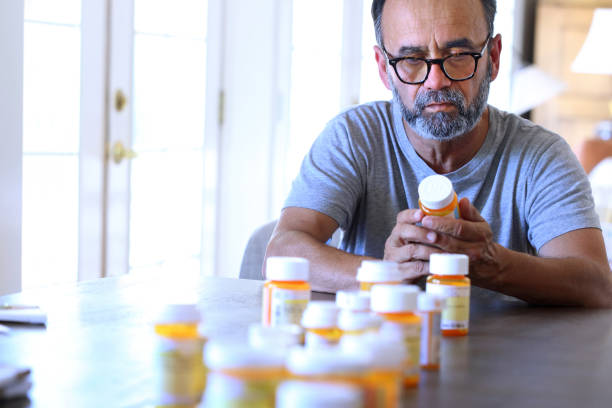istock Hispanic Man Sitting At Table Sorting Through Prescription Medications 2021300419