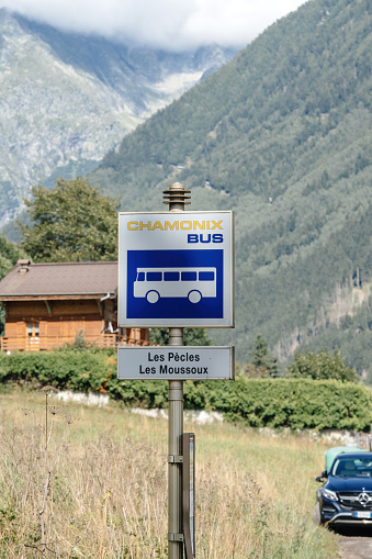Chamonix, France - Aug 12, 2017: Signage on pole with Chamonix Bus station les Pecles and Les Moussoux with tall mountains in background