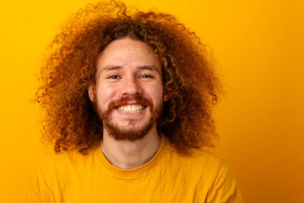 Smiling curly-haired man crossing fingers for good luck.