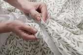 Woman is closing buttons on duvet cover while making the bed, close up