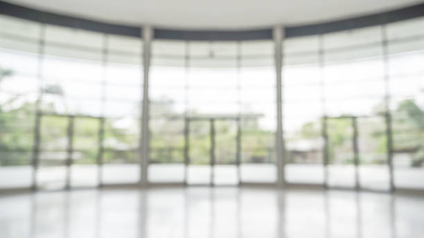 istock Office building lobby hall blur background or blurry school hallway corridor interior view looking toward empty corridor entrance, glass curtain wall and floor with exterior light illumination 2021348387