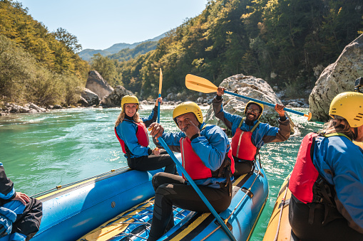 Showcasing the power of teamwork, a diverse mature group follows their guide’s lead on a whitewater rafting journey.