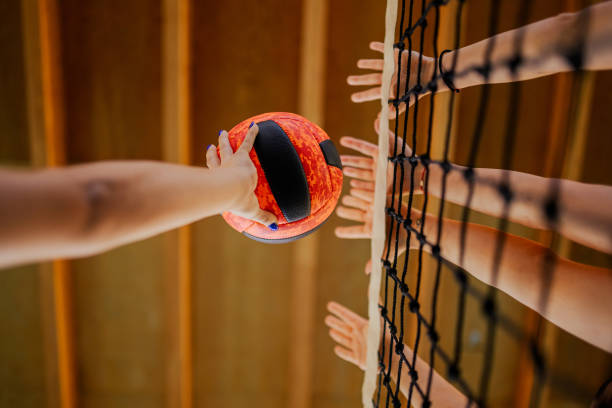 Close up of volleyball players' hands blocking a ball over net. Low angle view of a volleyball players' hands blocking a ball over the net on training. Close up of sportswomen hands with a volleyball blocking it over the volleyball net during the training. young volleyball girl stock pictures, royalty-free photos & images