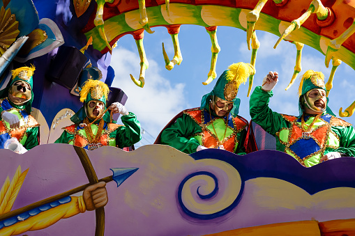 New Orleans, LA, USA - February 13, 2024: Rex krewe riders on a Mardi Gras float tossing beads to parade goers.