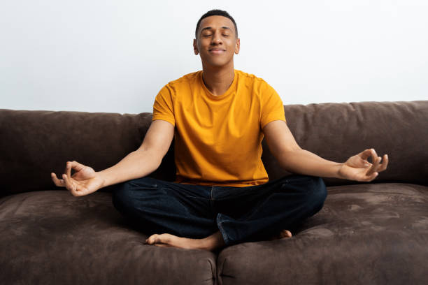 Attractive African American man sitting in lotus position, meditating with closed eyes