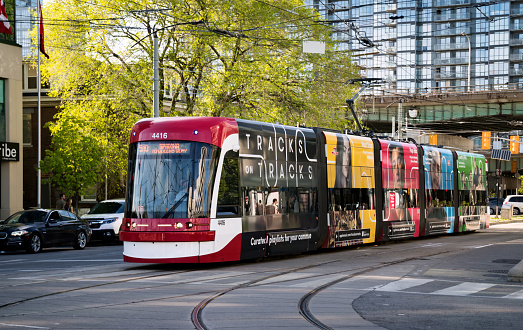 Toronto, Canada - 06 09 2019: A new Bombardier-made TTC streetcar with ad banners on its sides moving along the Spadina avenue in Toronto. Toronto Transit Commission is a public transport agency that operates bus, streetcar and subway