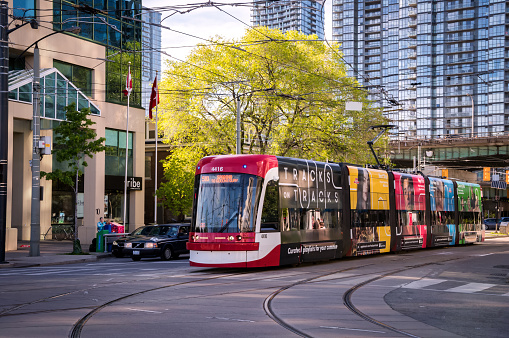 Toronto, Canada - 06 09 2019: A new Bombardier-made TTC streetcar with ad banners on its sides moving along the Spadina avenue in Toronto. Toronto Transit Commission is a public transport agency that operates bus, streetcar and subway