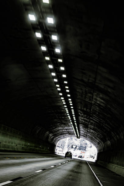 Black and white phot image of cars traveling through a tunnel in the mountains of colorful Colorado. No people. Copy space