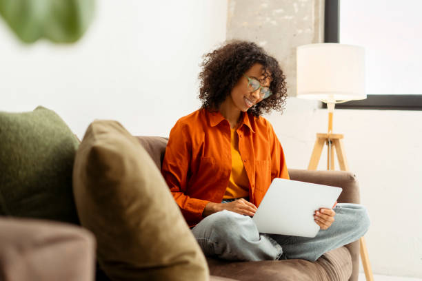 istock Smiling African American woman using laptop computer, typing, communication sitting in office 2021504259