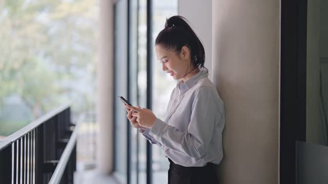 Businesswoman using her phone to read news or use apps on her smartphone outside her office