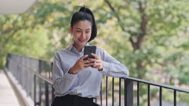 Businesswoman using her phone to read news or use apps on her smartphone outside her office
