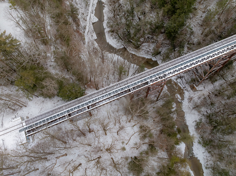 Winter aerial photos of a rusty old iron railway bridge over a forest valley