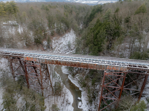 Winter aerial photos of a rusty old iron railway bridge over a forest valley