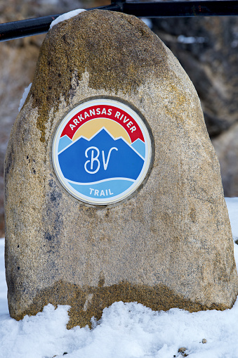 Buena Vista, Colorado, USA - February 10, 2024: Close-up view of a large rock with the “Arkansas River Trail BV” logo on it at the entrance to the Whipple Bridge that crosses the Arkansas River.