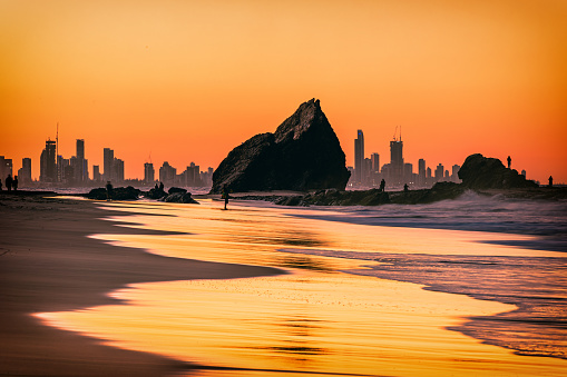 The sunset view of the Currumbin Beach in the twilight and the urban skyline of  Gold Coast in the dusk
