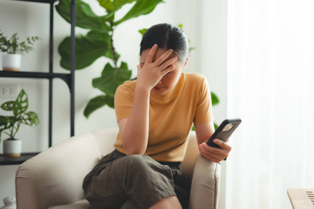 istock Asian woman sitting at home looking at smartphone screen and having problem. 2021785204