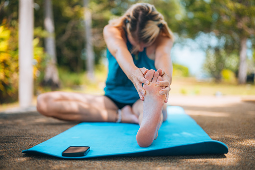 Young adult woman stretching in Head to Knee Pose (Janu Sirsasana) during her morning workout.