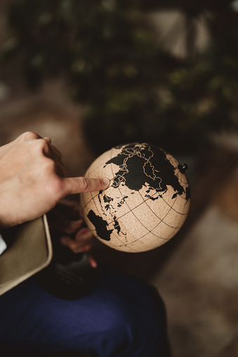 Vintage looking world globe with man pointing at Asia