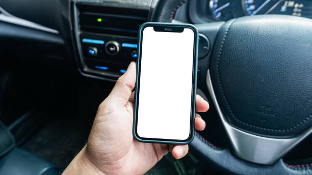istock Close-up image of Driver hand using blank white screen mobile smart phone inside a car. Man looking at smartphone screen searching location via gps navigator application 2021931673