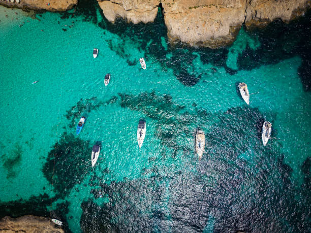 Experience serenity with an aerial view of a boats at Malta's Blue Lagoon, where crystal-clear waters and natural beauty create a mesmerizing scene.