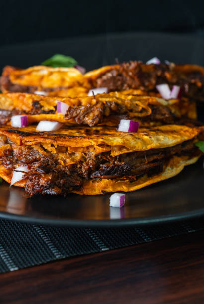 istock 3 Beef Birria Tacos Stacked on Black Plate 2021971499