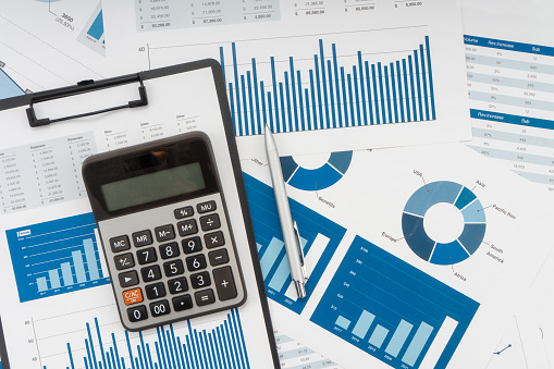 Calculator, glasses, pen and papers on white fading background with copy space. Business concept.