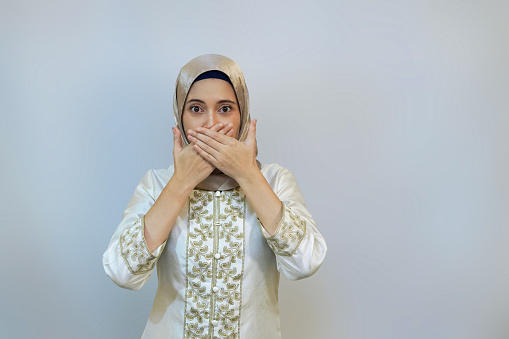 Woman covering ears, eyes, and mouth to shield from negativity, on white background