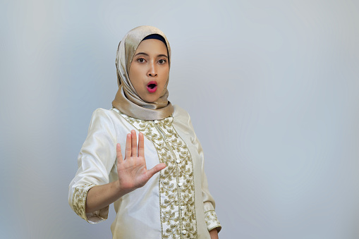 Indonesian woman posing with open palm as if prohibiting someone