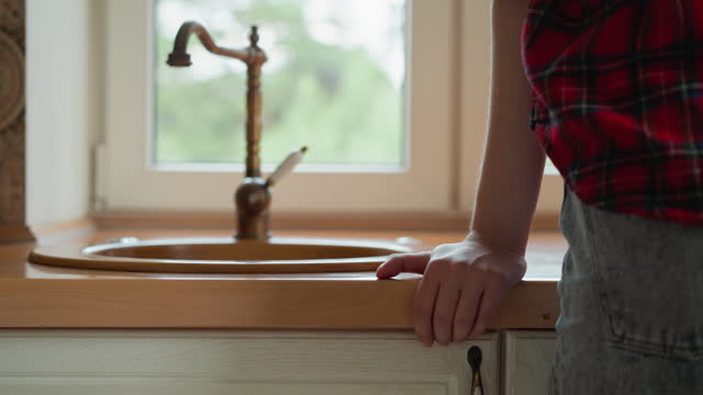 Woman stands by kitchen sink with vintage tap