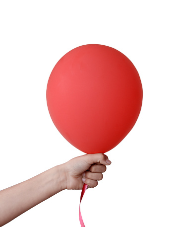 Vertical shot of cutout of one hand holding inflated fun red balloon in a fist isolated over white background with copy space,